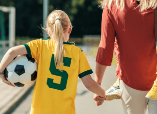Girl holding a soccer ball and mom's hand