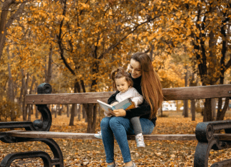 mother and child reading a book in the park, fall