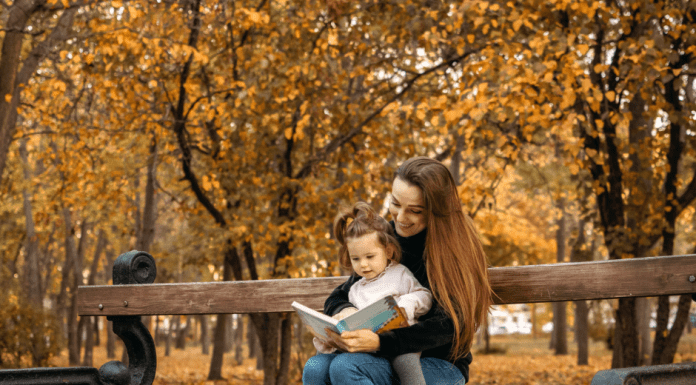 mother and child reading a book in the park, fall