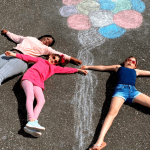 Child care provider making chalk art with two kids