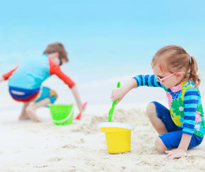 two kids playing on the beach making sand castles