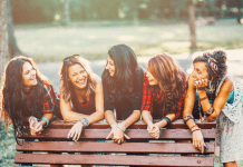 Group of women leaning on a park bench laughing