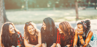Group of women leaning on a park bench laughing