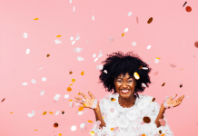 Celebrating happiness, young woman with big smile throwing confetti