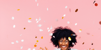 Celebrating happiness, young woman with big smile throwing confetti