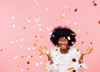 Celebrating happiness, young woman with big smile throwing confetti