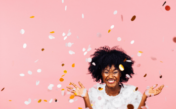 Celebrating happiness, young woman with big smile throwing confetti