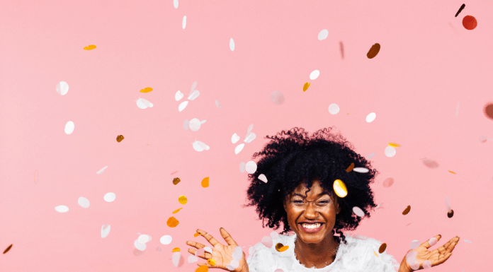 Celebrating happiness, young woman with big smile throwing confetti